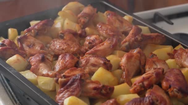 金属製のベーキングパンに鶏の羽で新鮮なロースト蒸しジャガイモ — ストック動画