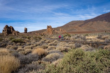 Tenerife, İspanya - 04.12.2023: Teide Ulusal Parkı, Tenerife, İspanya 'daki Roques de Garcia volkanik kayalarından yürüyüş yapan insanlar
