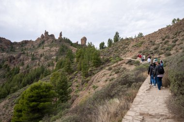 Gran Canaria, İspanya - 05.12.2023: İnsanlar İspanya 'nın Gran Canaria adasındaki Roque Nublo volkanik kayasına doğru yürüyüş yapıyorlar