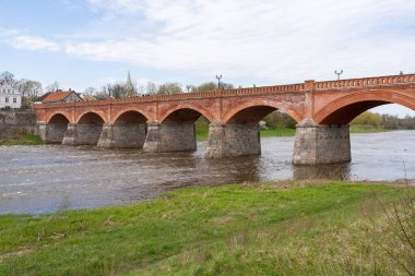 The old red brick bridge across the Venta river. Kuldiga, Latvia clipart