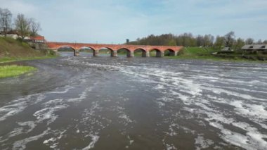 Venta nehri üzerinden Kuldiga, Letonya 'daki eski kırmızı tuğla köprüye doğru uçuyor.