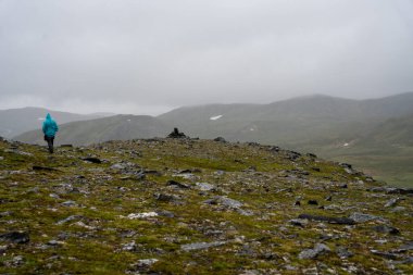 Norveç 'te Kirkeporten yolunda yağmurluk giyen bir turist.