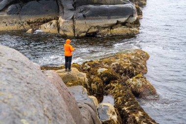 Norveç 'in Lofoten adalarındaki Svolvaer' de kayalıklarda balık tutan adam.