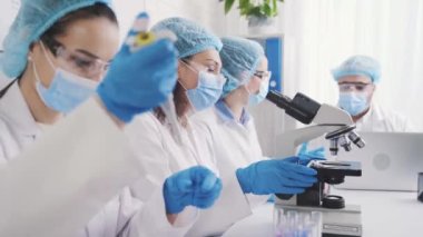asian female laboratory assistant with a laboratory dispenser conducts research under a microscope