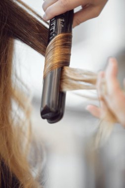 Saçı düz ütüyle şekillendiren birinin yakın çekimi..