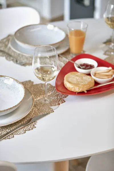 Şarap kadehleri, tabaklar ve içinde ekmek ve sos olan zarif bir yemek masası..