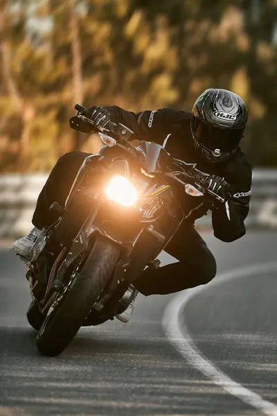 Bir motosikletlinin yola doğru keskin bir dönüş açısı var.