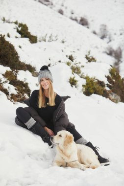 Karda altın av köpeğiyle gülümseyen kadın.