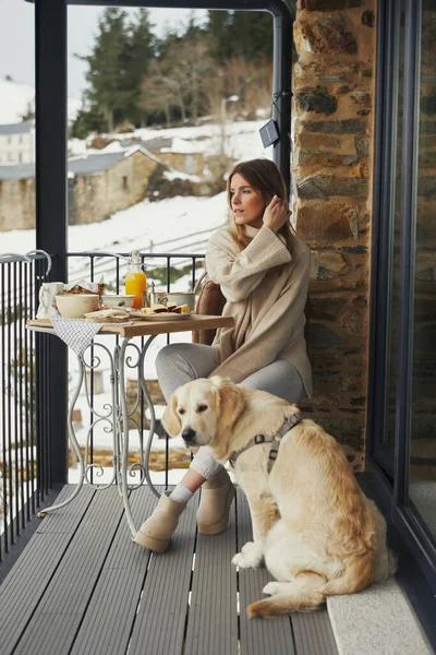 Köpekli kadın karlı balkon manzarasını seyrediyor..