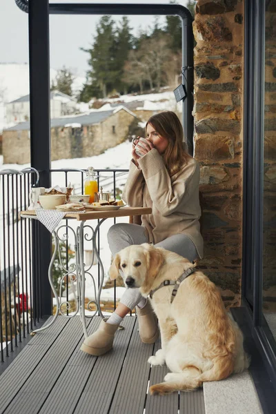 Köpekli kadın karlı balkon manzarasını seyrediyor..
