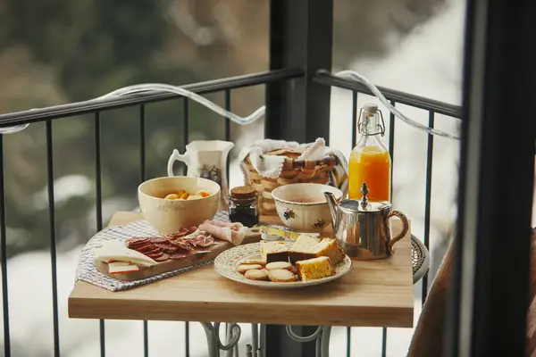 Karlı balkon korkuluklarına yayılmış zengin kahvaltı..