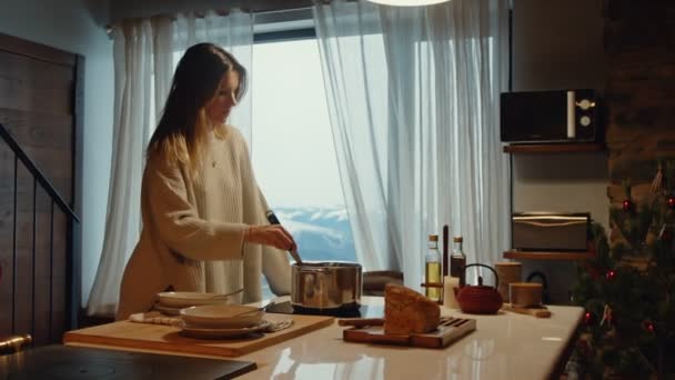宜人的冬季烹调 妇女在舒适的山地家庭厨房里准备食物 带着美丽的雪景 — 图库视频影像
