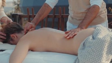 Outdoor Massage Therapy Session with Therapist Performing Back Massage on Relaxed Client by Wooden Fence