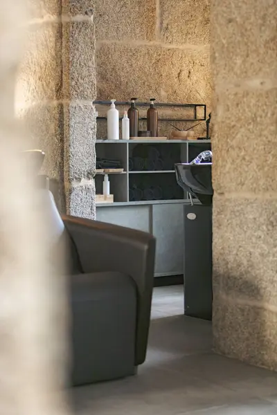 Bir saç yıkama istasyonu, havlulu raflar ve çeşitli saç bakım ürünlerinin yer aldığı şık bir salon manzarası.