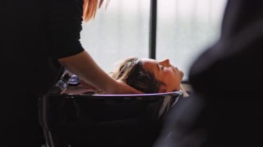 Bir kadın bir kuaförde rahatlatıcı bir saç yıkamadan zevk alır, bir an için kendine bakmanın ve şımartmanın altını çizer. Güzellik ve sağlık hizmetlerini desteklemek için mükemmel..