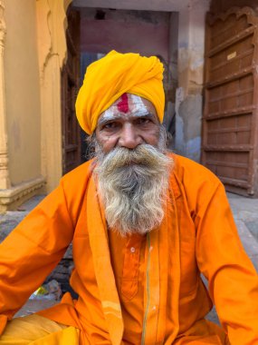 Pushkar, Rajasthan, Hindistan - Kasım 2022: Beyaz sakallı geleneksel safran elbiseli yaşlı bir sadhu baba portresi.
