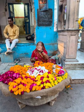 Pushkar, Rajasthan, Hindistan - Kasım 2022: Pushkar 'da dükkanın önünde oturan sokak satıcısı. Pushkar sokak pazarı yerli halk ve turistler arasında geleneksel ve etnik giysiler ve ürünlerle popüler.