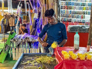 Pushkar, Rajasthan, Hindistan - Kasım 2022: Pushkar 'da dükkanın önünde oturan sokak satıcısı. Pushkar sokak pazarı yerli halk ve turistler arasında geleneksel ve etnik giysiler ve ürünlerle popüler.