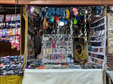 Pushkar, Rajasthan, Hindistan - Kasım 2022: Pushkar 'da dükkanın önünde oturan sokak satıcısı. Pushkar sokak pazarı yerli halk ve turistler arasında geleneksel ve etnik giysiler ve ürünlerle popüler.