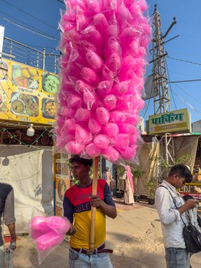 Pushkar, Rajasthan, Hindistan - Kasım 2022: Pushkar 'da dükkanın önünde oturan sokak satıcısı. Pushkar sokak pazarı yerli halk ve turistler arasında geleneksel ve etnik giysiler ve ürünlerle popüler.