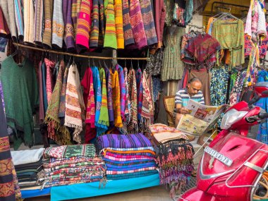 Pushkar, Rajasthan, Hindistan - Kasım 2022: Pushkar 'da dükkanın önünde oturan sokak satıcısı. Pushkar sokak pazarı yerli halk ve turistler arasında geleneksel ve etnik giysiler ve ürünlerle popüler.