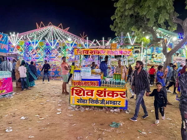 stock image Pushkar, Rajasthan, India - November 2022: Street vendor sitting outside the shop in Pushkar. Pushkar street market is popular among locals and tourists for traditional and ethnic clothes and items.