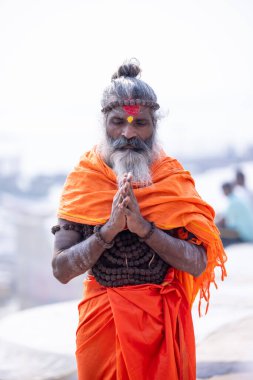 Varanasi, Uttar Pradesh, Hindistan - Kasım 2022: Tanınmayan Hint sadhu baba 'nın portresi gün doğumunda Varanasi şehrinde Ganj nehri kıyısındaki ghat üzerinde.