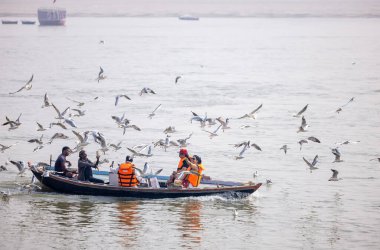 Varanasi, Uttar Pradesh, India - November 2022: Tourists enjoying boat side in the river ganges along with the herd of sea gulls at varanasi.