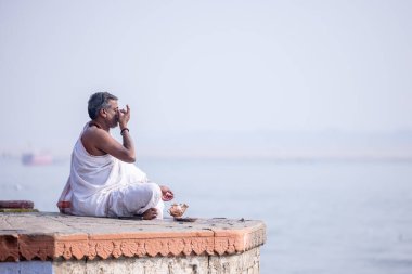 Varanasi, Uttar Pradesh, India - November 2022: Portrait of Unidentified Indian brahmin priest on ghat near river ganges in varanasi city.
