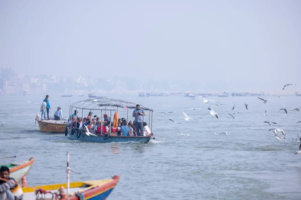Varanasi, Uttar Pradesh, India - November 2022: Tourists enjoying boat side in the river ganges along with the herd of sea gulls at varanasi.