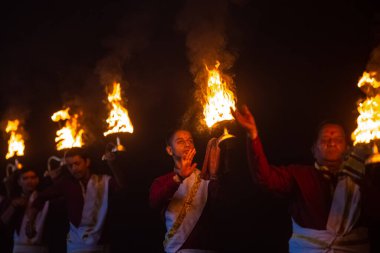 Rishikesh, Uttarakhand, India - October 2022: Portrait of hindu male priests performing river Gange aarti with fire flame in hands at triveni ghat to worship river ganges. Ganga aarti performed in night.