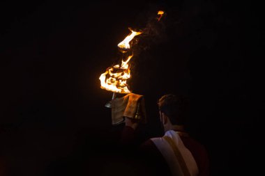 Rishikesh, Uttarakhand, India - October 2022: Portrait of hindu male priest performing river Gange aarti with fire flame in hand at triveni ghat to worship river ganges. Ganga aarti performed in night