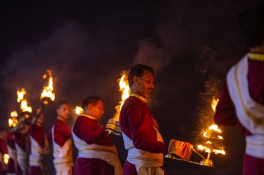 Rishikesh, Uttarakhand, India - October 2022: Portrait of hindu male priests performing river Gange aarti with fire flame in hands at triveni ghat to worship river ganges. Ganga aarti performed in night.