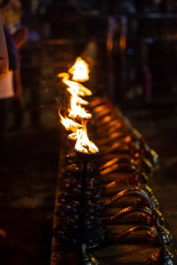 Fire flame at night with dark background during the ganga aarti rituals at river bank.