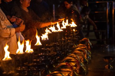 Rishikesh, Uttarakhand, India - October 2022: Portrait of hindu male priest performing river Gange aarti with fire flame in hand at triveni ghat to worship river ganges. Ganga aarti performed in night