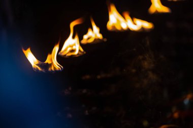 Fire flame at night with dark background during the ganga aarti rituals at river bank.