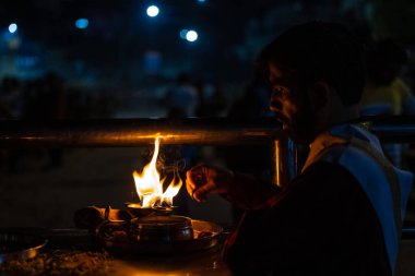 Rishikesh, Uttarakhand, India - October 2022: Portrait of hindu male priest performing river Gange aarti with fire flame in hand at triveni ghat to worship river ganges. Ganga aarti performed in night