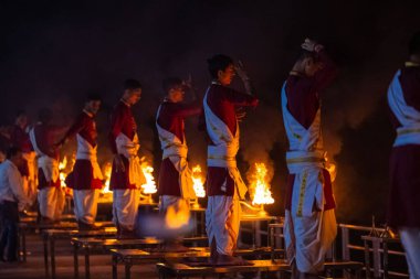 Rishikesh, Uttarakhand, India - October 2022: Portrait of hindu male priests performing river Gange aarti with fire flame in hands at triveni ghat to worship river ganges. Ganga aarti performed in night.