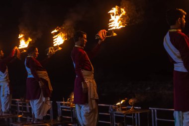Rishikesh, Uttarakhand, India - October 2022: Portrait of hindu male priests performing river Gange aarti with fire flame in hands at triveni ghat to worship river ganges. Ganga aarti performed in night.