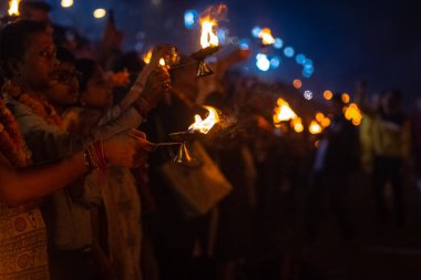 Rishikesh, Uttarakhand, India - October 2022: Portrait of hindu male priests performing river Gange aarti with fire flame in hands at triveni ghat to worship river ganges. Ganga aarti performed in night.
