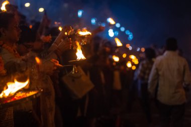 Rishikesh, Uttarakhand, India - October 2022: Portrait of hindu male priests performing river Gange aarti with fire flame in hands at triveni ghat to worship river ganges. Ganga aarti performed in night.