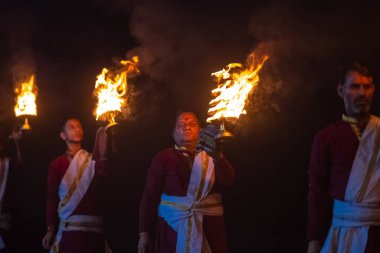 Rishikesh, Uttarakhand, India - October 2022: Portrait of hindu male priests performing river Gange aarti with fire flame in hands at triveni ghat to worship river ganges. Ganga aarti performed in night.