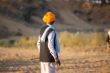 Pushkar, Rajasthan, India - November 2022: Pushkar Fair, camel trader in ethnic dress at fair ground during pushkar fair.