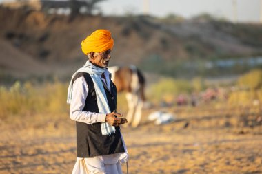 Pushkar, Rajasthan, India - November 2022: Pushkar Fair, camel trader in ethnic dress at fair ground during pushkar fair.