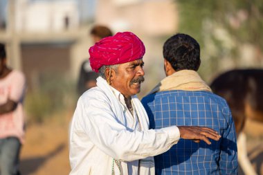 Pushkar, Rajasthan, India - November 2022: Pushkar Fair, camel trader in ethnic dress at fair ground during pushkar fair.