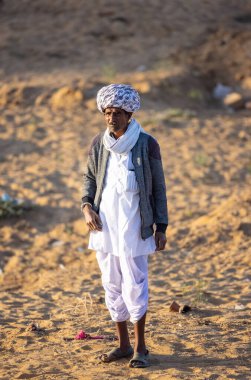 Pushkar, Rajasthan, India - November 2022: Pushkar Fair, Portrait of an camel trader in ethnic dress and rajasthani turban on fair ground during pushkar fair.