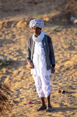 Pushkar, Rajasthan, India - November 2022: Pushkar Fair, Portrait of an camel trader in ethnic dress and rajasthani turban on fair ground during pushkar fair.