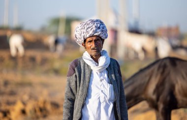 Pushkar, Rajasthan, India - November 2022: Pushkar Fair, Portrait of an camel trader in ethnic dress and rajasthani turban on fair ground during pushkar fair.