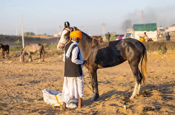 Pushkar, Rajasthan, India - November 2022: Pushkar Fair, camel trader in ethnic dress at fair ground during pushkar fair.