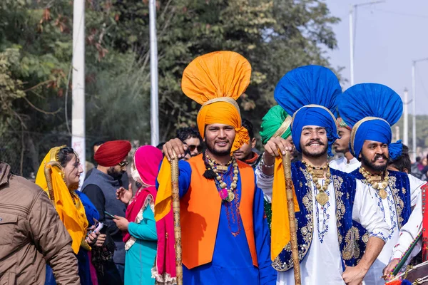 stock image Bikaner, Rajasthan, India - January 2023: Punjabi Bhangra, Portrait of young sikh male in traditional punjabi colorful dress and turban performing bhangra dance with smile in camel festival with focus